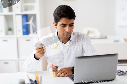 Image of businessman with laptop eating fruits at office