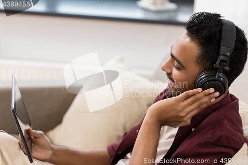 Image of man in phones with tablet pc listening to music