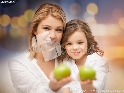 Image of happy mother and daughter with green apples