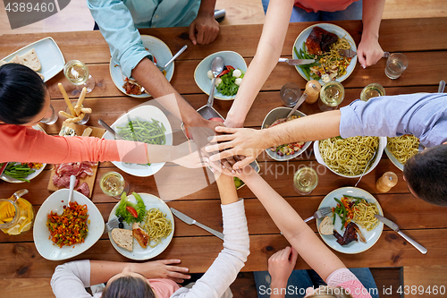 Image of people holding hands together over table with food