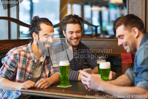 Image of friends with smartphone drinking green beer at pub