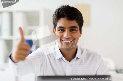 Image of businessman showing thumbs up at office