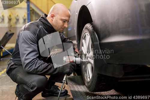 Image of auto mechanic with screwdriver changing car tire