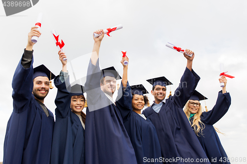 Image of happy students in mortar boards with diplomas