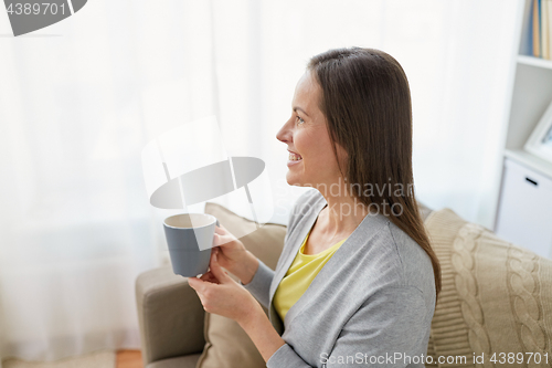 Image of happy woman drinking tea or coffee at home