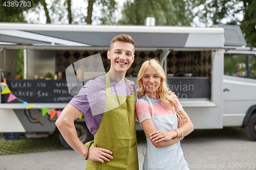 Image of happy couple of young sellers at food truck