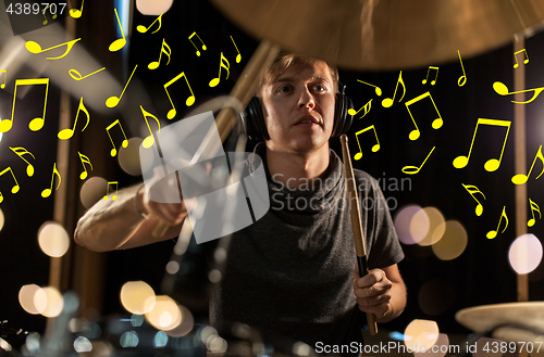 Image of musician in headphones playing drum kit at concert