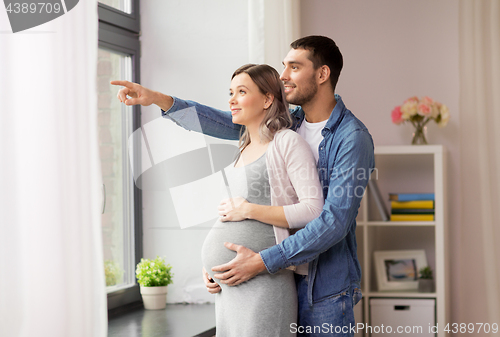 Image of man showing something out window to pregnant wife