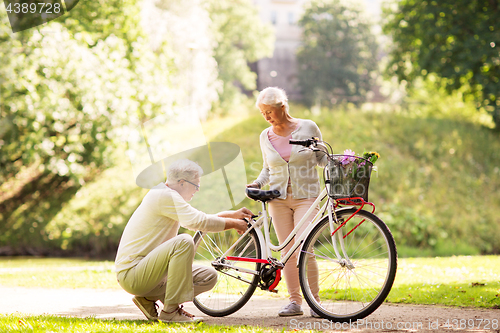 Image of happy senior couple with bicycle at summer park