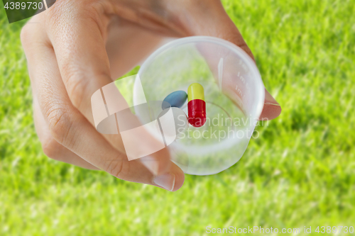 Image of close up of female hand with pills in medicine cup