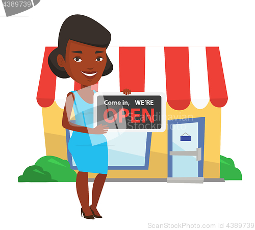 Image of African shop owner holding open signboard.