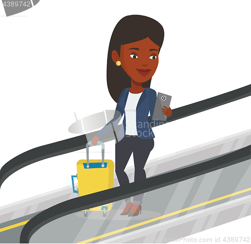 Image of Woman using smartphone on escalator in airport.