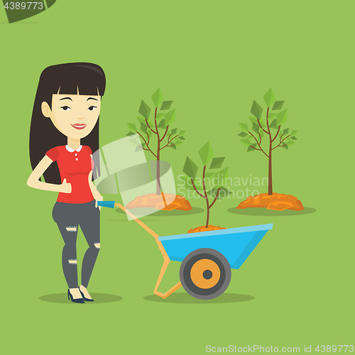 Image of Woman pushing wheelbarrow with plant.