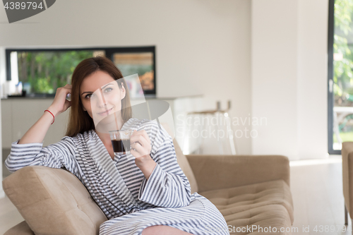 Image of young woman in a bathrobe enjoying morning coffee