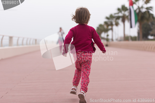 Image of mother and cute little girl on the promenade by the sea