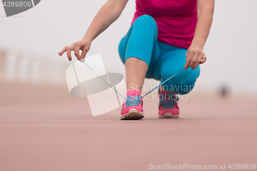 Image of Young woman tying shoelaces on sneakers