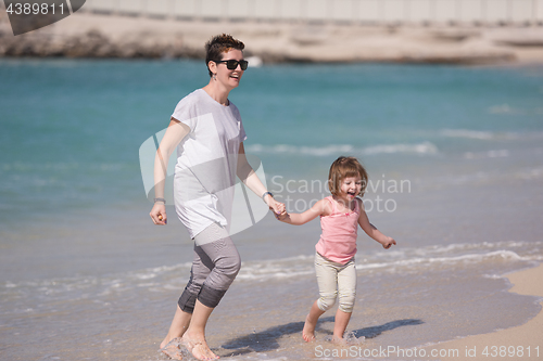 Image of mother and daughter running on the beach