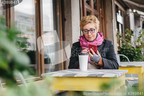 Image of Adult woman with coffee and smartphone