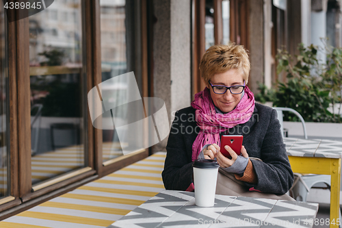 Image of Adult woman with coffee and smartphone