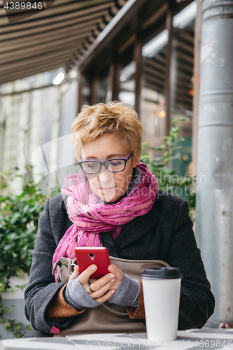 Image of Smiling woman with phone in cafe