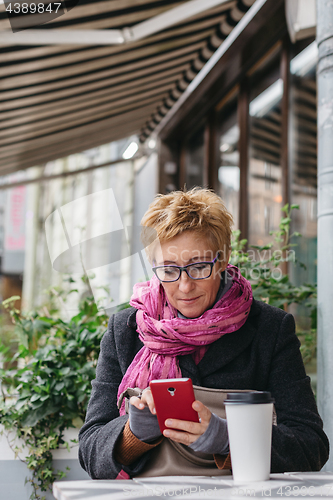 Image of Smiling woman with phone in cafe