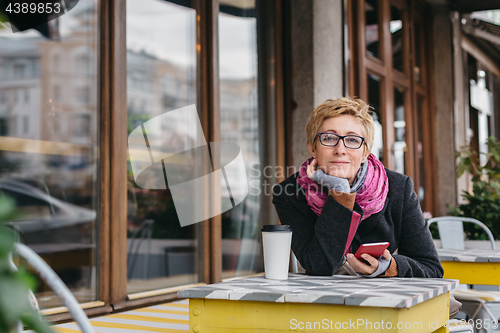 Image of Dreamy woman with phone in cafe