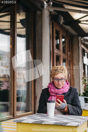 Image of Woman with drink and smartphone