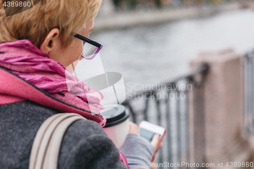 Image of Woman using smartphone at river