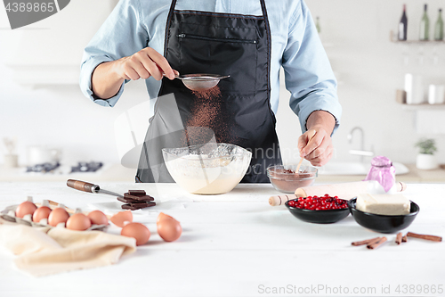 Image of A cook with eggs on a rustic kitchen against the background of men\'s hands