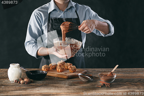 Image of Decorating delicious homemade eclairs with chocolate and peanuts