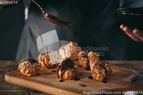 Image of Decorating delicious homemade eclairs with chocolate and peanuts