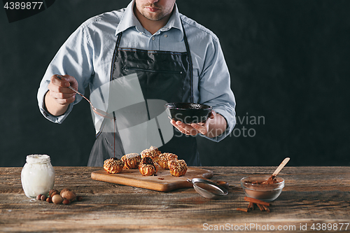Image of Decorating delicious homemade eclairs with chocolate and peanuts