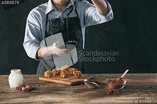 Image of Decorating delicious homemade eclairs with chocolate and peanuts