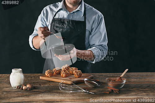 Image of Decorating delicious homemade eclairs with chocolate and peanuts