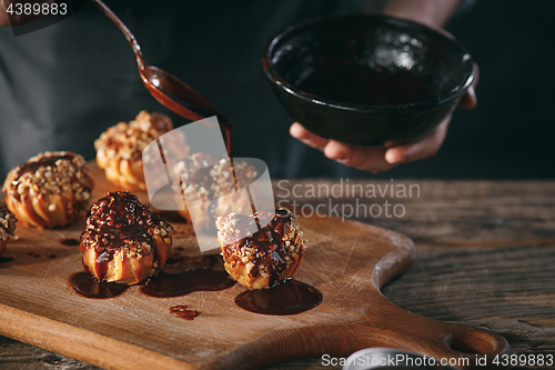 Image of Decorating delicious homemade eclairs with chocolate and peanuts