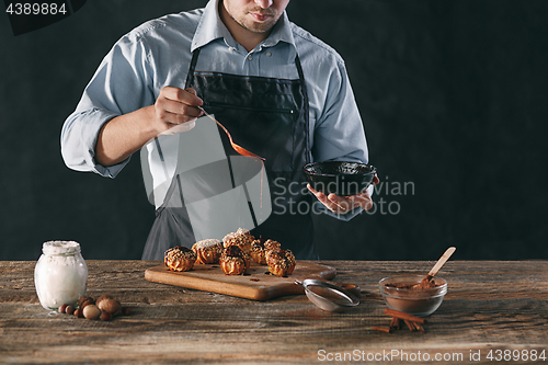 Image of Decorating delicious homemade eclairs with chocolate and peanuts