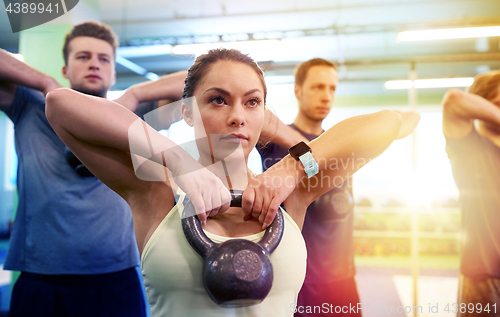 Image of group of people with kettlebells exercising in gym