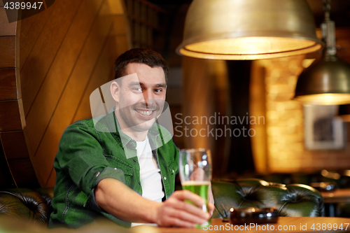 Image of man drinking green beer at bar or pub