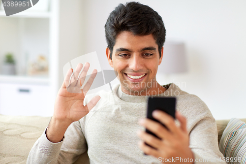 Image of happy man having video call on smartphone at home