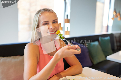 Image of happy young woman eating at restaurant