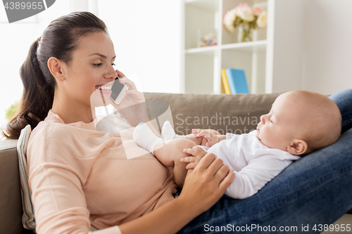 Image of mother with baby calling on smartphone at home