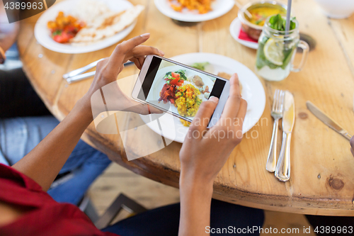 Image of hands with smartphone picturing food at restaurant