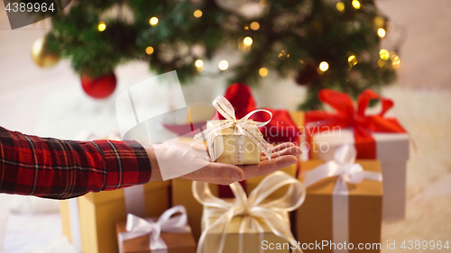 Image of close up of hand holding small christmas gift box