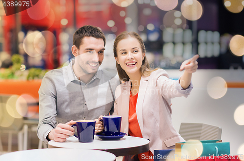 Image of happy couple with shopping bags drinking coffee