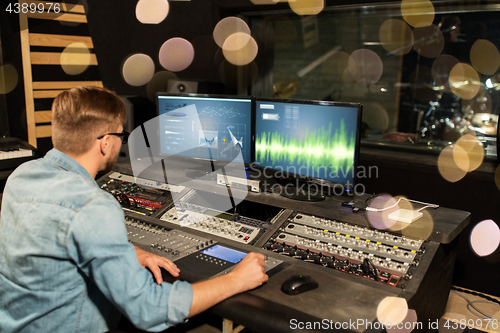 Image of man at mixing console in music recording studio