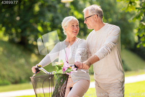 Image of happy senior couple with bicycle at summer park