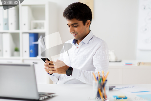 Image of businessman messaging on smartphone at office