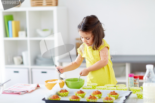 Image of little girl baking muffins at home