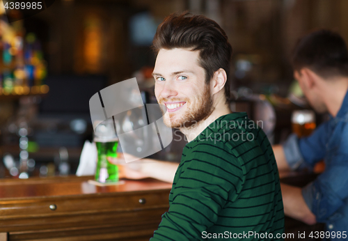 Image of happy man drinking green beer at bar or pub