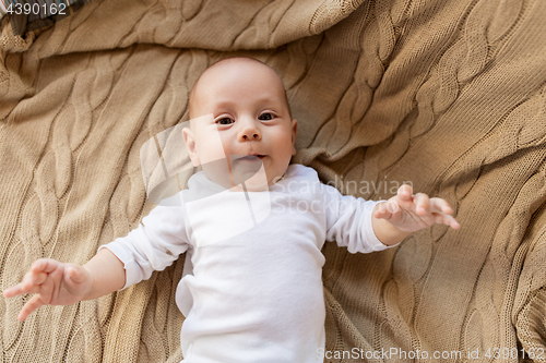 Image of sweet little baby boy lying on knitted blanket